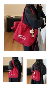 Close-up of red canvas tote bag with Banatu logo and white moon plush pendant