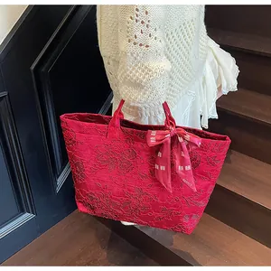 Dettaglio borsa tote in jacquard rosso a fiori con sciarpa decorativa in seta e motivi xi
