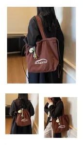 Detailed view of deep brown nylon tote bag featuring drawstring closure and cloud charm