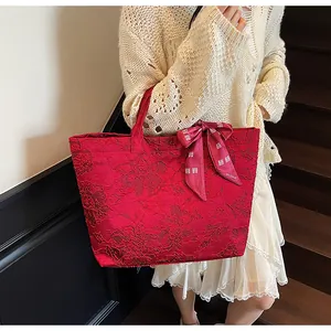 Dettaglio borsa tote jacquard rossa con foulard a fiocco tenuta su una scala