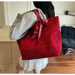 Dettaglio della borsa tote in jacquard rosso con fiocco festivo e trama floreale elegante