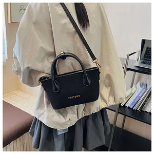 Détail du sac bandoulière noir matelassé avec logo doré et poignée supérieure élégante
