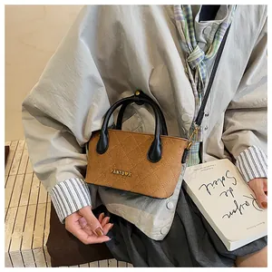 Gros plan d'un sac bandoulière marron matelassé avec logo doré et poignées en cuir noir