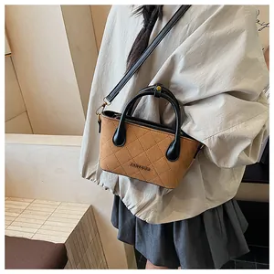 Gros plan d'un sac seau en daim marron avec surpiqûres en losanges et poignées noires