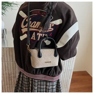 Détail du sac cabas beige matelassé avec logo en métal doré et finitions en cuir noir