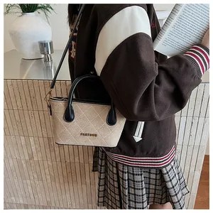 Détail du sac beige matelassé avec poignées noires et logo doré sur veste collège