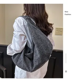 Detail of dark grey washed denim hobo bag showing casual slouchy drape and soft texture