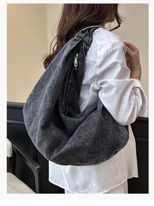 Detail of large dark grey denim tote bag with metal zipper and washed texture