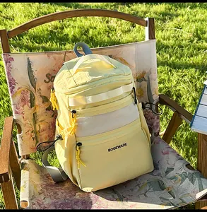 Close-up of a pale yellow outdoor backpack with mesh pockets on a wooden chair