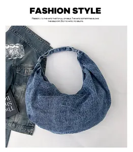 Flat lay of a large blue denim tote bag with washed texture and seamless shoulder strap