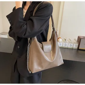 Detail of mocha brown leather hobo bag with silver chain and baseball charm