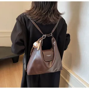 Detail view of large brown oil wax leather tote with a baseball bat keychain accessory