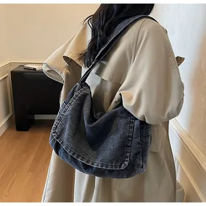 Detail of dark blue washed denim shoulder bag showing flap design and adjustable strap
