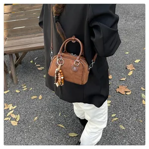 Close-up of brown suede pillow bag with decorative bead tassel and leather strap