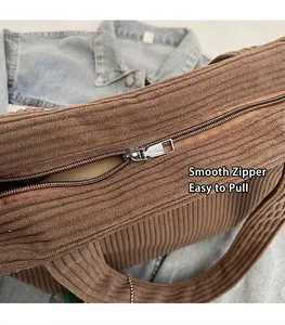 Detail shot of smooth metal zipper and inner lining on dark brown corduroy tote bag