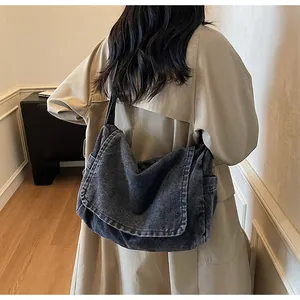 Detail of dark denim crossbody bag with flap closure and washed texture on side pocket