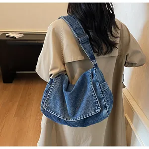 Detail of blue denim crossbody bag with adjustable strap and washed texture on a model