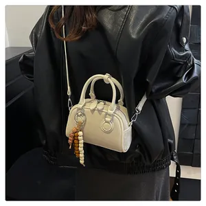 Detail of off-white retro pillow bag with textured surface and beaded tassel charm