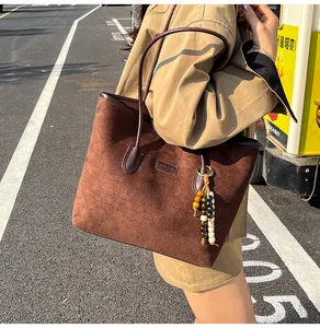 Detail of dark brown suede tote bag with stylish wooden bead tassel charm in sunlight