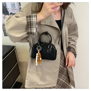Model wearing a black canvas pillow bag with a colorful beaded pendant charm