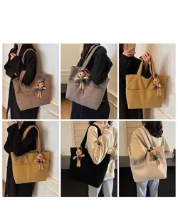 Detail view of corduroy tote bags with rabbit charms in coffee, gray, yellow, black and beige