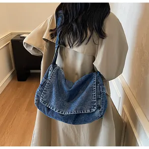Detail view of large denim shoulder bag with flap closure and functional side pocket