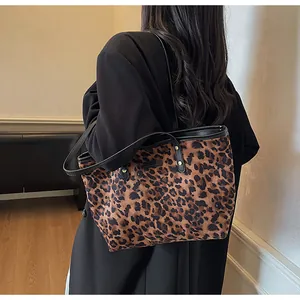 Détail d'un cabas à imprimé léopard avec bandoulières en cuir noir et rivets dorés