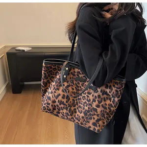 Détail du sac cabas léopard avec anses en cuir noir et rivets dorés élégants
