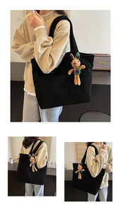 Detail view of black corduroy tote bag texture with a cute stuffed rabbit charm accessory