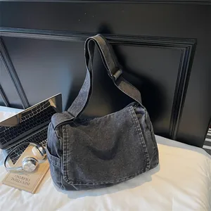 Retro washed denim messenger bag with large capacity for women next to laptop and books