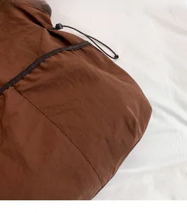 Detail of dark brown lightweight fabric with adjustable drawstring toggle and stitching