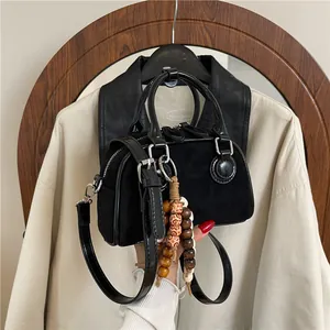 Chic black suede hobo bag with patent leather handles and ethnic wooden bead charm