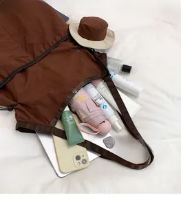 Deep brown canvas tote bag interior showing capacity with umbrella and daily essentials