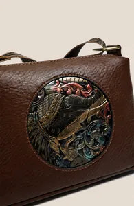 Detail of retro leather bag featuring an embossed elephant motif and vintage strap