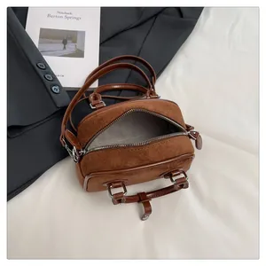 Vintage brown leather doctor bag with suede stitching and dual zippers on white background