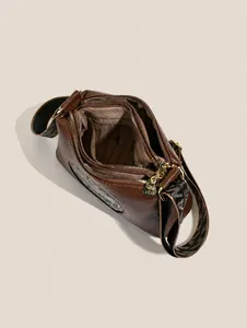 Internal view of brown leather bag with three compartments and woven shoulder strap
