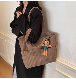 Detail of dark brown corduroy tote bag with soft texture and cute plush bunny charm pendant