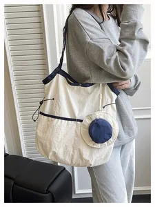 Detail of minimalist canvas tote bag featuring navy blue piping and a side drawstring
