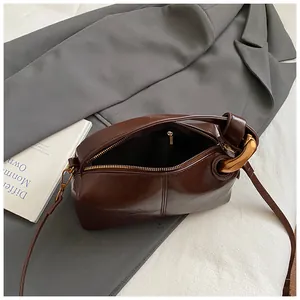 Top view of deep brown leather pillow bag with gold ring and zipper detail