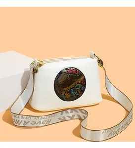 Detail of white cross-body bag featuring vintage relief and three-zipper design