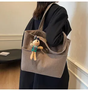 Detail of brown corduroy tote bag featuring soft texture and cute rabbit plush accessory