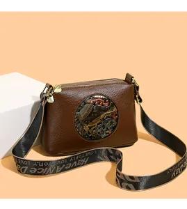 Detail of vintage brown leather bag with elephant embossment and triple zipper design
