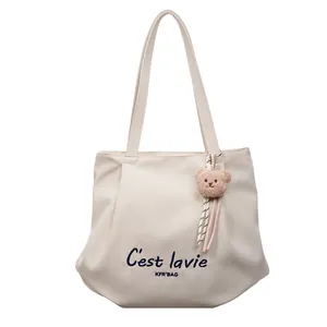 Minimalistische gebroken witte canvas emmer tas met blauwe letters en beer hanger