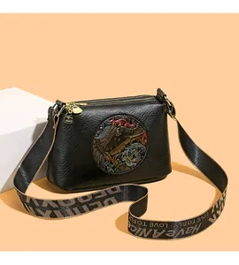 Detail of black leather bag with colorful round relief and branded kangaroo pendant