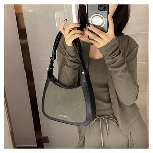 Détail d'un sac demi-lune en daim vert avec des bandoulières en cuir noir
