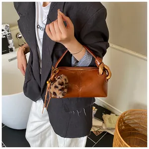 Close-up of brown vintage leather bag with leopard print pompom and knot detail