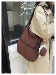 Detail of dark brown canvas tote bag featuring side pockets and leather reinforced straps