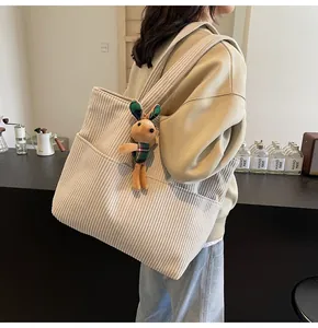 Corduroy tote bag details showing large outer pocket and cute plush bunny charm accessory