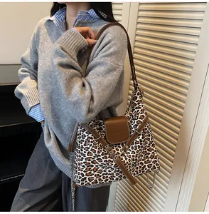 Detail of leopard print tote bag with brown leather trim and metal chain shoulder strap