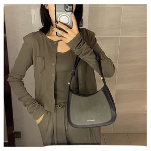 Selfie miroir montrant un sac selle demi-cercle en tissu vert foncé et cuir noir